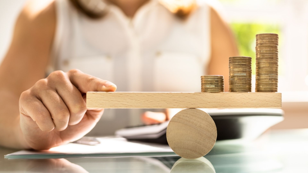 Mão feminina equilibrando a balança financeira.